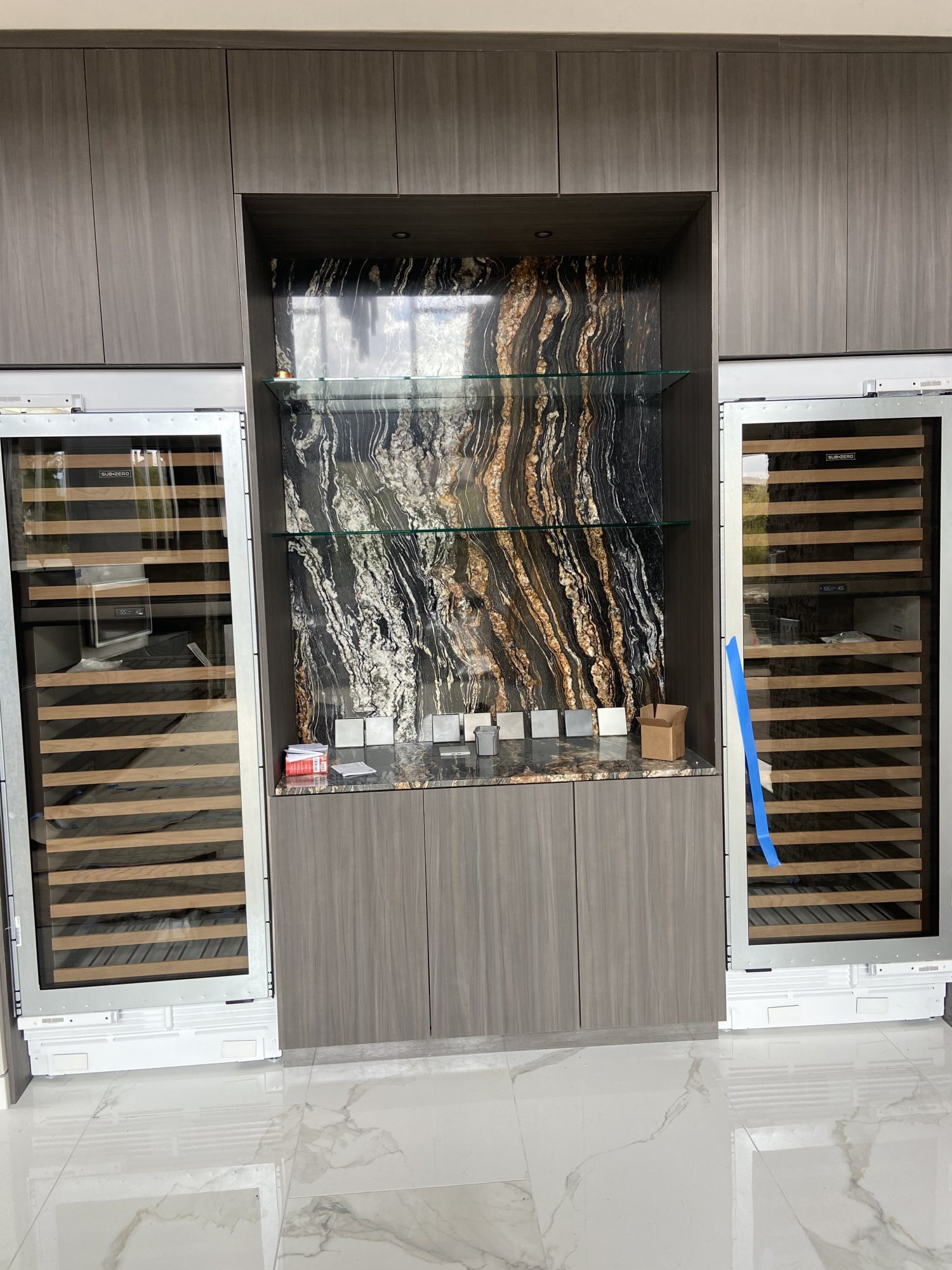 Bookmatched stone feature wall in a wet bar with wine columns